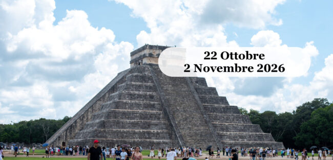 La piramide di El Castillo a Chichén Itzá, nello Yucatán, sotto un cielo azzurro, con i visitatori sul prato ai suoi piedi