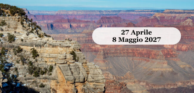 Il Grand Canyon visto dal bordo sud, con gli strati di roccia rossa e ocra che scendono verso il fondo del canyon sotto un cielo azzurro